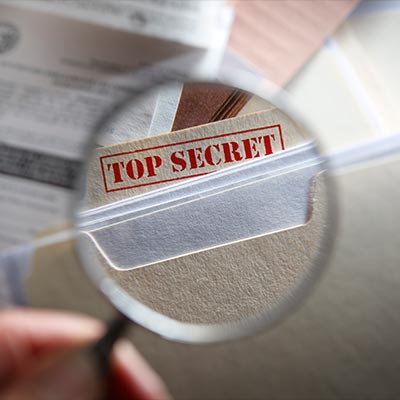 Someone looking at top secret files with magnifying glass stock photo